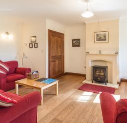 A living room with red sofas a wooden coffee table a fireplace and a television at Ridge Cottage in Whitridge