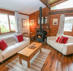 A living room with two white sofas and a wood burning stove at Timbertwig Lodge in Lamphey near Pembroke