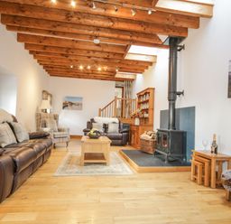 A living room with leather sofas a wood stove and wooden ceiling beams at Pendre Uchaf in Melin-y-Wig near Ruthin