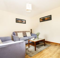 A living room with two sofas a coffee table with cups and flowers a TV on a wooden stand and landscape pictures on the wall at The Shippon Near Launceston