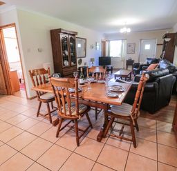 A dining area with a wooden table set for four and a living room with black leather sofas at Drovers Rest in Otterburn