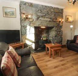 A living room with a sofa, television, and fireplace at Tyddyn in Dyffryn Ardudwy