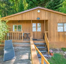 A wooden cottage with outdoor seating and lounge chairs on a deck at Bluebell Cottage in Maenan near Llanrwst