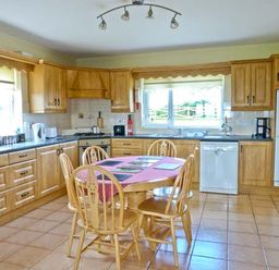 A kitchen with wooden cabinets a table with chairs and appliances at Sallywood House in Carn near Ballybofey County Donegal
