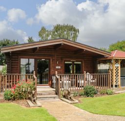 A wooden lodge with a porch and garden statues in front at Cornfield in Northallerton