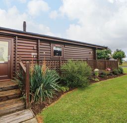 A wooden cabin with stairs and a garden in front at Cornfield in Northallerton