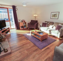 A living room with a sofa, armchair, and television at The Old Grainstore in Bolton Low Houses near Wigton