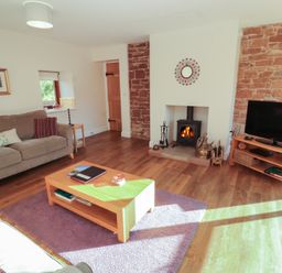 A living room with a sofa and a fireplace at The Old Grainstore Bolton Low Houses near Wigton