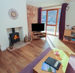 A living room with a fireplace and television at The Old Grainstore Bolton Low Houses near Wigton