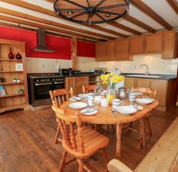 A kitchen with wooden dining table set for breakfast wooden chairs wooden cabinets and a wooden shelf at The Farmhouse in Aberaeron