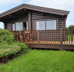 A wooden cabin with a porch and garden plants at Ty Pren in Llanrhian near St Davids
