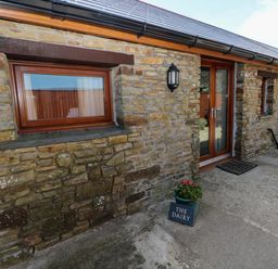 An exterior view featuring a stone wall and entrance door at The Dairy near Penuel Llanmorlais