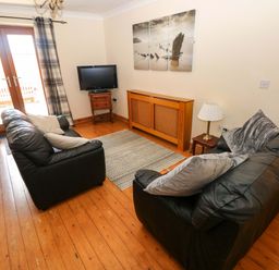 A living room with a sofa and television at The Dairy in Penuel near Llanmorlais