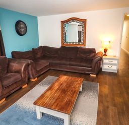 A living room with brown sofas wooden coffee table wall clock and a mirror at Greyhound Barn Barnsley near Cirencester