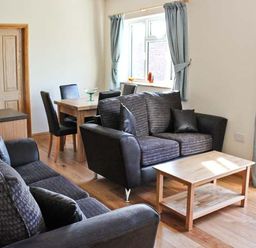 A living room with sofas a wooden coffee table and a dining table with chairs at Moat Farm Cottage in Wood Dalling