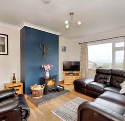 A living room with black leather sofas a wood burning stove and a television at Pen Y Gaer in Llannefydd near Abergele and Denbigh