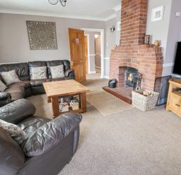 A living room with leather sofas wooden coffee table brick fireplace and television at Beach Cottage in Conwy