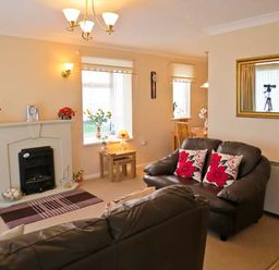 A living room with leather sofas cushions and a fireplace at Sunrise in Kessingland near Lowestoft