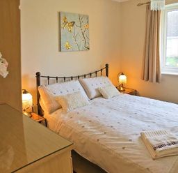A bedroom with a double bed bedside tables with lamps and a window at Sunrise in Kessingland near Lowestoft