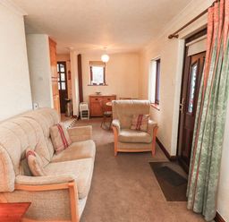 A living room with a sofa and armchair at Ghyll Bank Bungalow Staveley near Windermere