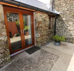 An outdoor area with a wooden door and stone walls at The Stall in Penuel near Llanmorlais