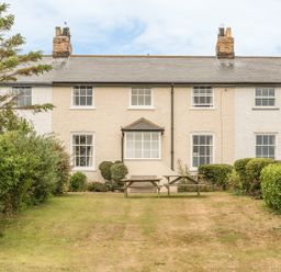 A garden with picnic tables in front of a row of terraced houses at Coastguard Cottage in Low Newton-by-the-Sea near Beadnell