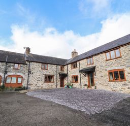 Stone farm house with multiple windows and slate roof with gravel courtyard at Maestyddyn Farm House in Clawddnewydd near Ruthin