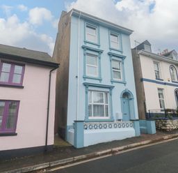 A street view of three attached houses with one blue house in the center at Dunholme House in Teignmouth