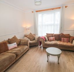 A living room with brown sofas a round coffee table and two lamps at Dunholme House in Teignmouth