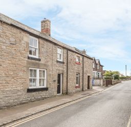 A street view with stone houses and a paved sidewalk at Fisherman's Cottage in Seahouses