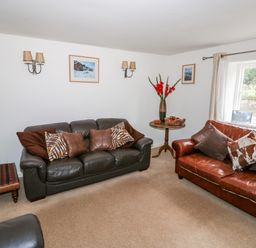 A living room with two sofas and pillows near a window and side tables at Manor Farm Cottage in Swaffham