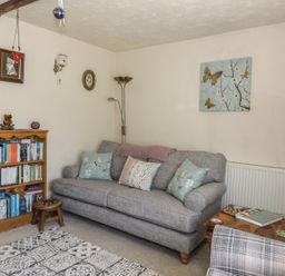 A living room with a gray sofa and bookshelf at Megs Cottage in Norwich