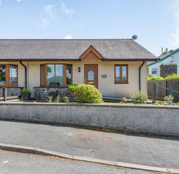 A single-story house with brown framed windows a brown door and a low concrete wall at Gorwel in Llan Ffestiniog near Blaenau Ffestiniog