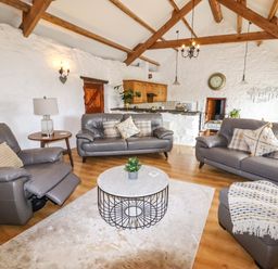 A living room with gray sofas a round coffee table and wooden beams at Y Bwthyn in Ysbyty Ifan