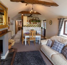 A living room with a sofa and dining table in a cottage at Cwm Derw Cottage in Llanafan Fawr near Builth Wells