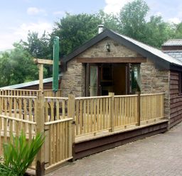 A wooden deck with a table and chairs outside a stone and wood house at Cwm Derw Cottage in Llanafan Fawr near Builth Wells