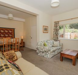 A living room featuring a sofa, dining area and television at Gardener's Cottage in Llanwrthwl near Rhayader