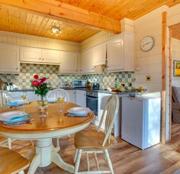 A kitchen and dining area with a round table set for four and a living room with a sofa at Apple Tree Lodge Swarland near Alnwick