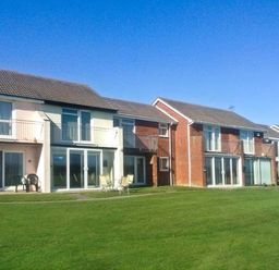 A row of two story houses with balconies and patios overlooking a grassy lawn at Seascope in Kessingland near Lowestoft