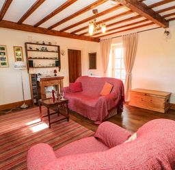 A living room with two covered sofas a wooden coffee table a TV stand with television and a rug at Cherry Tree Cottage in Soulby near Kirkby Stephen