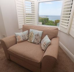 A living room with an armchair and cushions at Apartment 1 Llewellan in St Ives