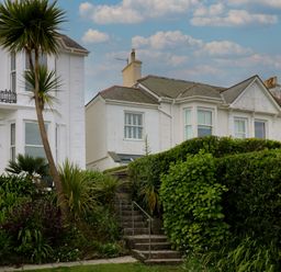 A house with a balcony and palm trees at Apartment 1 Llewellan in St Ives