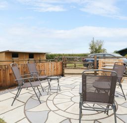 An outdoor seating area with chairs and a table at The Log Cabin in Bushton near Royal Wootton Bassett