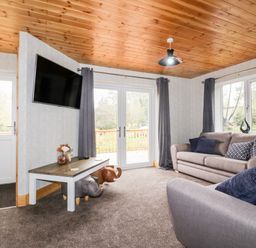 A living room with two sofas a wall mounted TV and a coffee table at Lodge One in Brighton near Summercourt