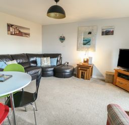 A living room with a sofa and TV at Beach View in Benllech near Red Wharf Bay