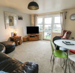 A living room with a television and dining table at Beach View in Benllech near Red Wharf Bay