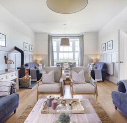 A living room with multiple armchairs sofas a wood stove and a large window at Ty Carmel in Rhosneigr