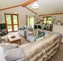 A living room with two sofas a wooden coffee table a television and a dining area at The Beeches in Narberth