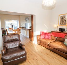 A living room with a brown leather chair and sofa with pillows next to a wooden dining table at Lightkeeper House in Amble-by-the-Sea