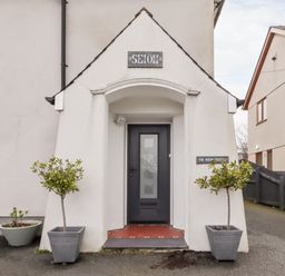 Front entrance of a house with a black door and two potted plants at Yr Hen Festri in Y Felinheli
